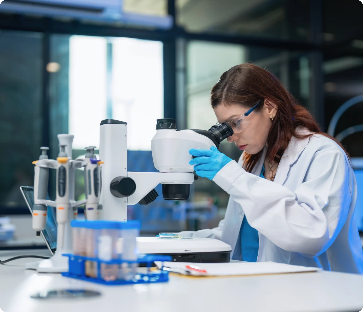 Scientist examining sample under a microscope.